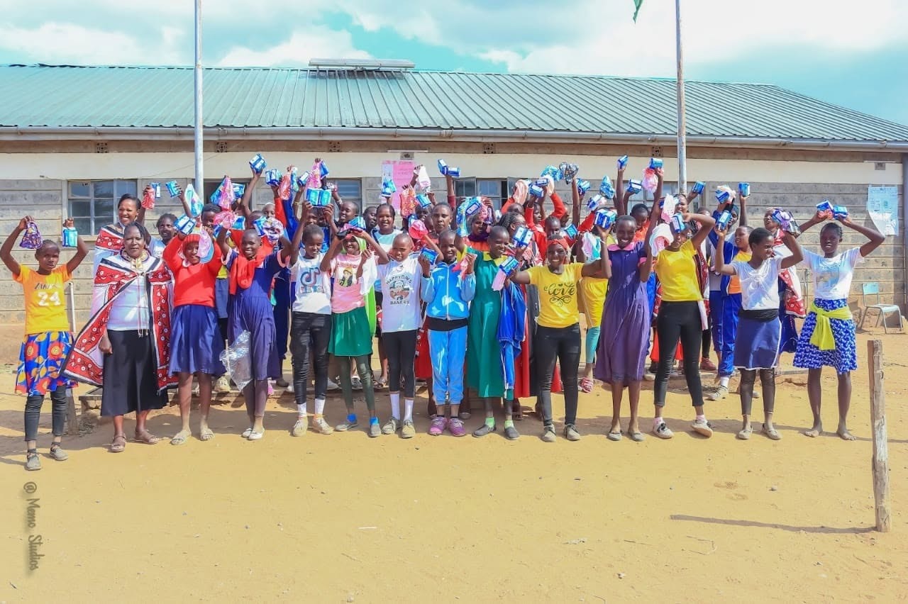 Women and girls holding menstrual dignity support supplies